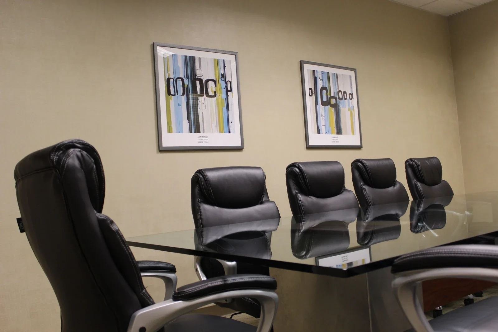 Padded conference chairs and glass table with framed artwork.
