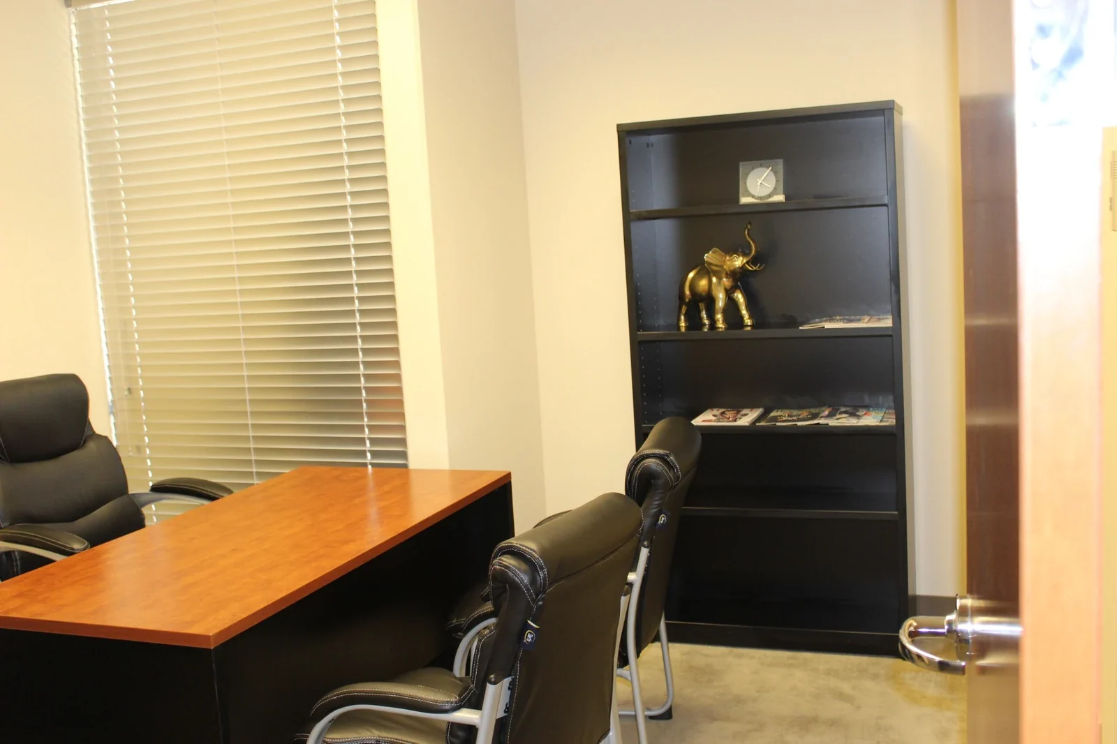 Day Office with a wood-top desk, guest chairs, window and black bookcase.